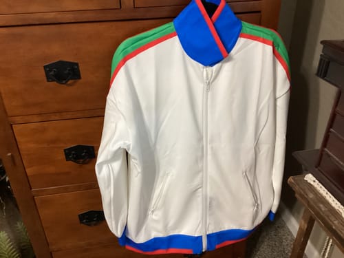 Reviewer's photo of a white zip-up jacket with blue, green, and red accents.