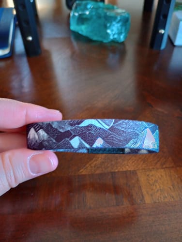 Close-up of a reviewer holding the One More Step Bracelet to show the detailed mountain pattern.