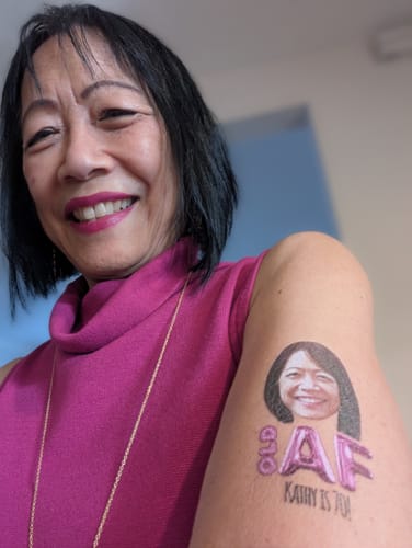 Reviewer smiling and showing the custom 'Old AF' birthday tattoo on her arm, which has her face on it.