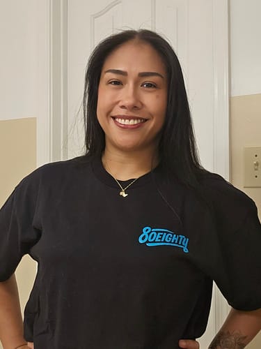 Reviewer smiling while wearing the black 80Eighty® DreamBig Boxy Shirt, showing the blue logo on the chest.