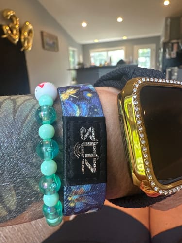 Close-up of a reviewer's wrist wearing a patterned Hope Pack bracelet next to a watch.