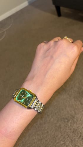 Customer wearing the CLAIRE DE MAINS watch with a green face and two-tone band on their wrist.