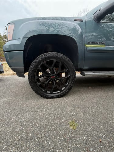 Customer's close-up of the front wheel and tire on a lifted gray Sierra, showing clearance from the suspension kit.