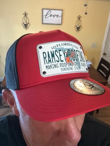 Customer wearing a red and black Florida Plate Hat with a customized 'Ramsey Roofing' patch.