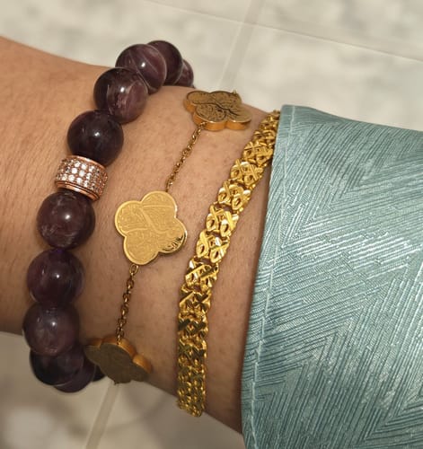 Customer's wrist showing the thin, gold Sabr, Shukr, Tawakkul Bracelet layered with other jewelry.