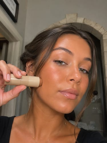 Reviewer applying the Lunéra Hudtint Stick to their cheek, showing a natural, dewy finish.