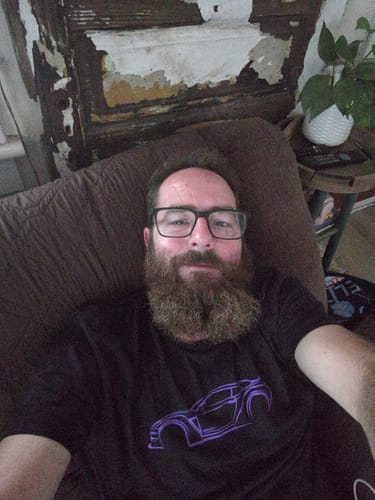 Reviewer relaxing on a couch while wearing the black 80Eighty® DCG88 Shirt with a purple graphic.