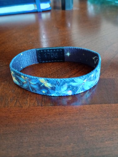 Customer's Dreams Become Wings Bracelet with a blue dragonfly pattern resting on a dark wood table.
