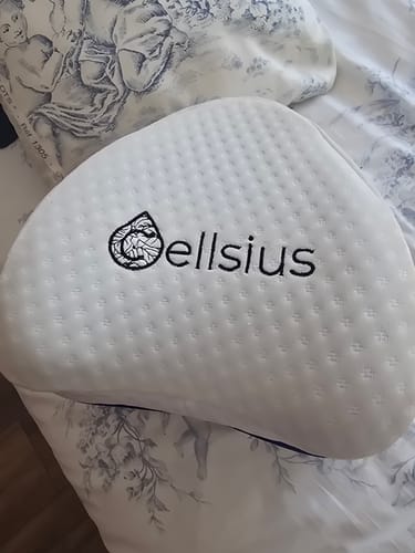 Un client montre le coussin pour genoux Cellsius avec sa housse blanche et texturée posée sur un lit.