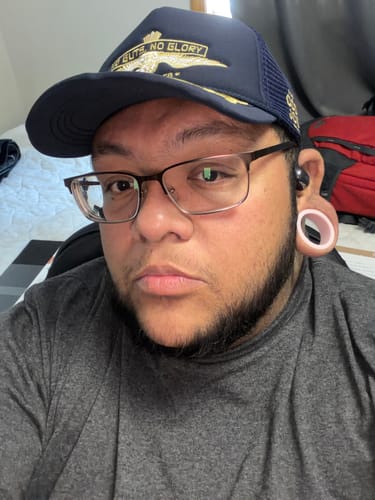 Reviewer in a close-up photo wearing the dark blue Big Foam Military Trucker Hat, showing its fit.
