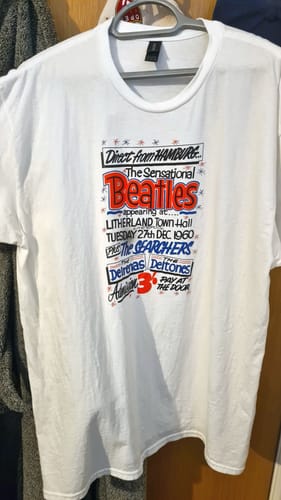 Reviewer's white unisex t-shirt on a hanger, showing the detailed 'The Beatles' graphic print.
