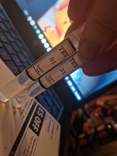 Customer holding two 5ml perfume samples, including the 'Inspired by Good Girl - 81' vial.