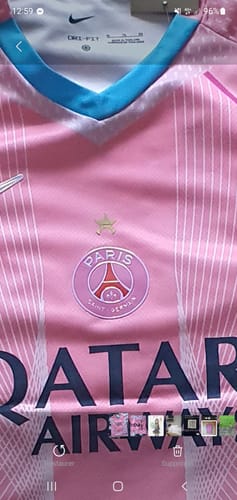Gros plan par un client du maillot PSG rose, montrant l'étoile au-dessus de l'écusson qui se décolle légèrement.