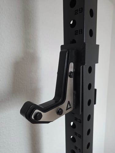 Rezensent zeigt den hochwertigen R7 J-Hook mit schwarzem Finish und Edelstahl-Detail an einem Rack.