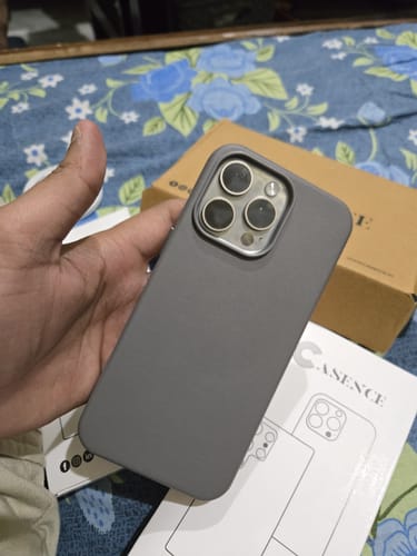 Reviewer holding the graphite grey Signature Leather Magsafe Case on an iPhone, showcasing its sleek design.