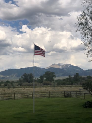 Customer's Betsy Ross Flag flying on a flagpole with a mountain landscape in the background.