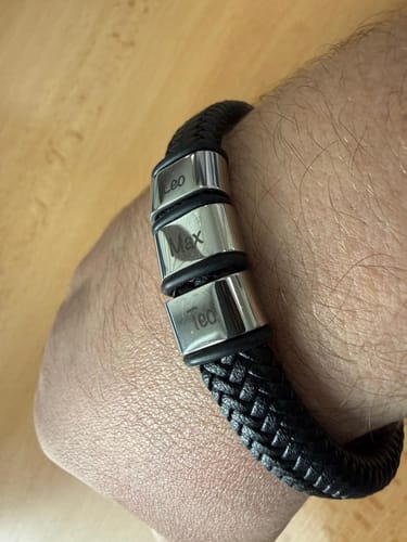 Customer wearing the black braided Viking Bracelet on their wrist, showing three silver beads engraved with names.