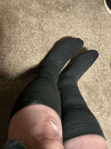 Reviewer wearing the black Eucalyptus Lyocell Compression Socks pulled up to their knees on a carpeted floor.