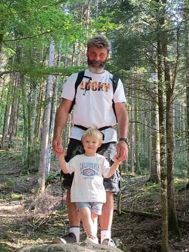 Un client portant le t-shirt blanc de la collection LUCKY avec un enfant dans une forêt verdoyante.