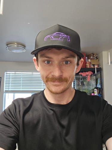 Reviewer wearing the black DCG88 Hat with a purple embroidered car design.