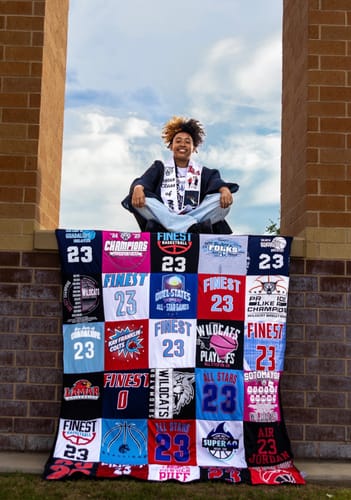 A reviewer's graduate sits behind their large Project Repat T-Shirt Quilt made from colorful basketball jerseys.