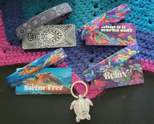 Customer's Go With The Flow Sea Turtle Pack laid out, showing four colorful bracelets with their cards and a silver turtle keychain.