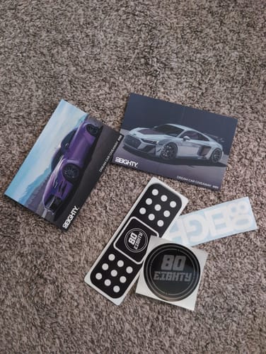 Customer's 80Eighty Bandaid Vinyl Sticker laid out with other branded stickers and promotional cards on a carpet.