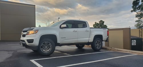 Customer's white Chevy Colorado with the lift kit and 33-inch tires installed, parked in a lot.