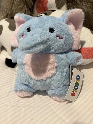 Customer's adorable OLAOLA elephant plush toy in light blue and pink, sitting on a bed.