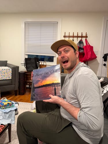 Customer happily holding a custom vinyl record with a personalized sunset album cover.