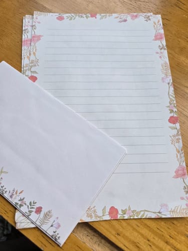 Customer's Vintage Botanical Letter set showing lined paper with a floral border and a matching envelope on a table.