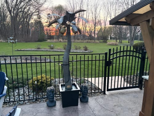 Reviewer's patio setup showing the solar light mounted atop a metal palm tree at sunset.