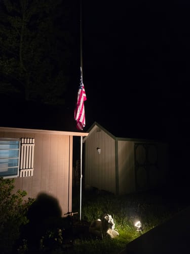 Reviewer's American flag hanging on a flagpole, illuminated by a light from below at night.