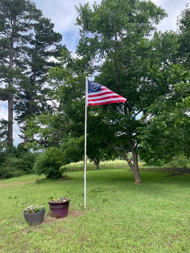 Customer's sewn Betsy Ross Flag flying on a flagpole in a grassy outdoor area.
