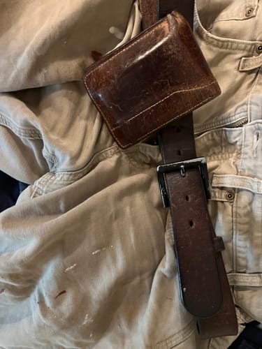 Customer's well-worn brown leather belt and matching wallet, demonstrating durability after a decade of use.