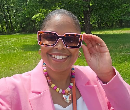 Close-up of a customer smiling while wearing the stylish, color-block Deco Sunglasses outdoors.