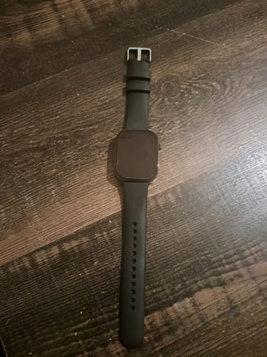 Customer's black Gard Pro Health Smartwatch 3 with the screen off, laid on a dark wood surface.