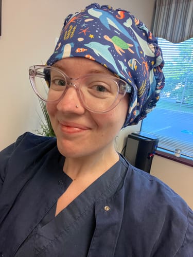 Reviewer in scrubs smiling while wearing the DuoStyle Scrub Hat in the Sea Life pattern.
