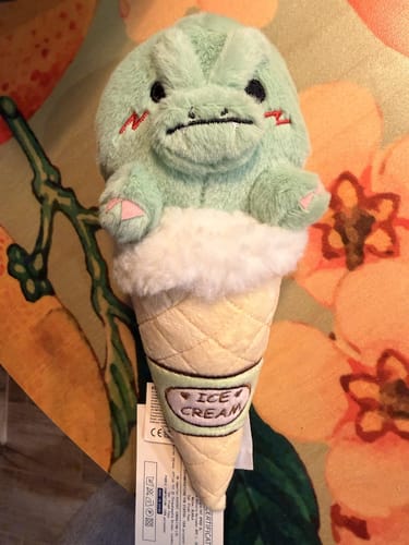 Customer's adorable dinosaur ice cream plush toy with a spunky expression on a floral surface.