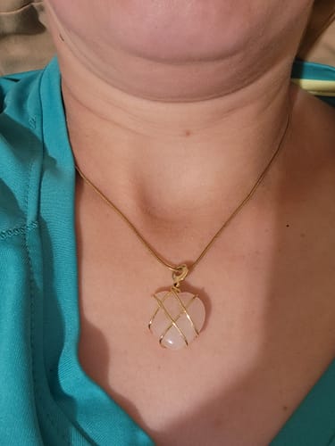Customer wearing the monthly crystal, a pink heart-shaped pendant with a gold-wire wrap on a gold chain.