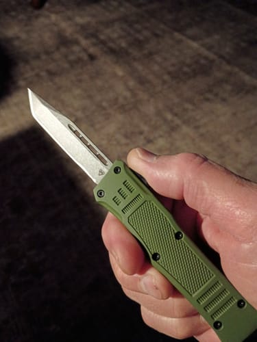 Reviewer holding the Small Green Phantom OTF knife, showing its green handle and deployed tanto blade.