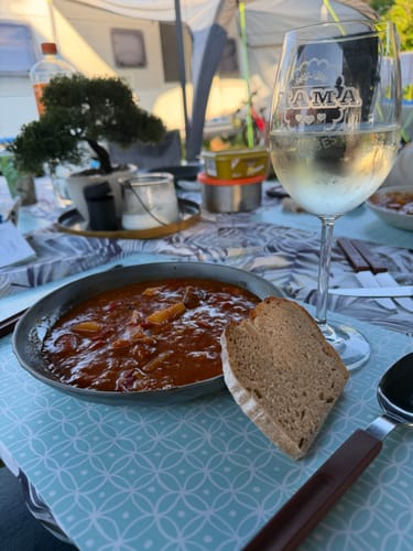 Kunde zeigt ein graviertes Leonardo Weinglas mit Weißwein während einer Mahlzeit im Freien.