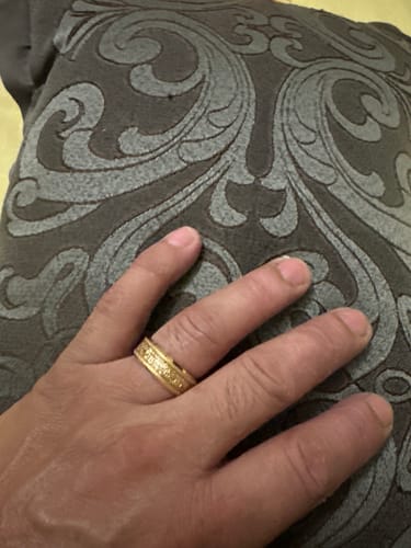 Customer's hand wearing the gold Aureum ring with its sandblasted texture and foil inlay visible against a dark patterned background.