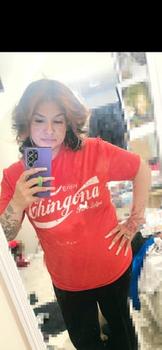 Reviewer posing in a mirror while wearing the red Chingona Refresco Vintage Tee.