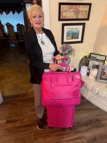 Reviewer with her bright pink Weekender Bag slid over the handle of a matching rolling suitcase.
