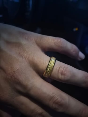 Close-up of a customer wearing the gold Aureum ring with a textured inlay on their finger in a dark setting.