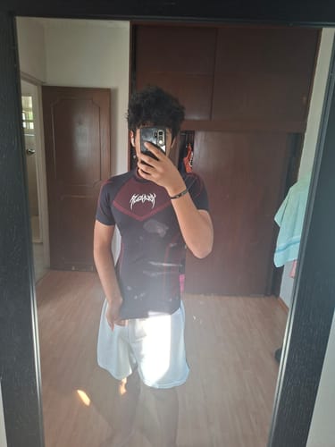 Reviewer in a mirror selfie shows the fit of their dark Warrior X Compression Tee.