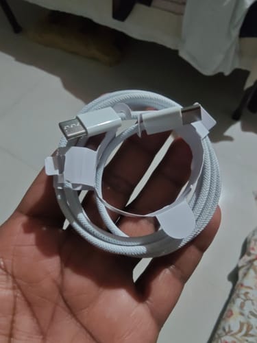 Customer holds the white, braided Casence Armor Type C to C charging cable coiled in its holder.