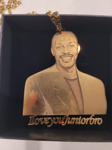 Customer's gold-colored photo engraved pendant with a man's portrait and custom text, shown in its black gift box.