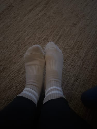 Customer wearing the light-colored, striped Dual-Direction Grip Basics socks on their feet.